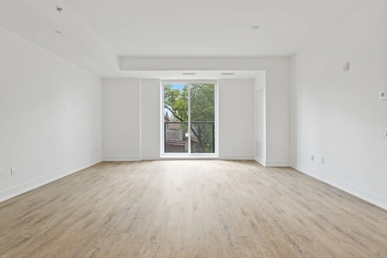 Unfurnished room with a wood-look floor and a large window, illustrating a factual room description