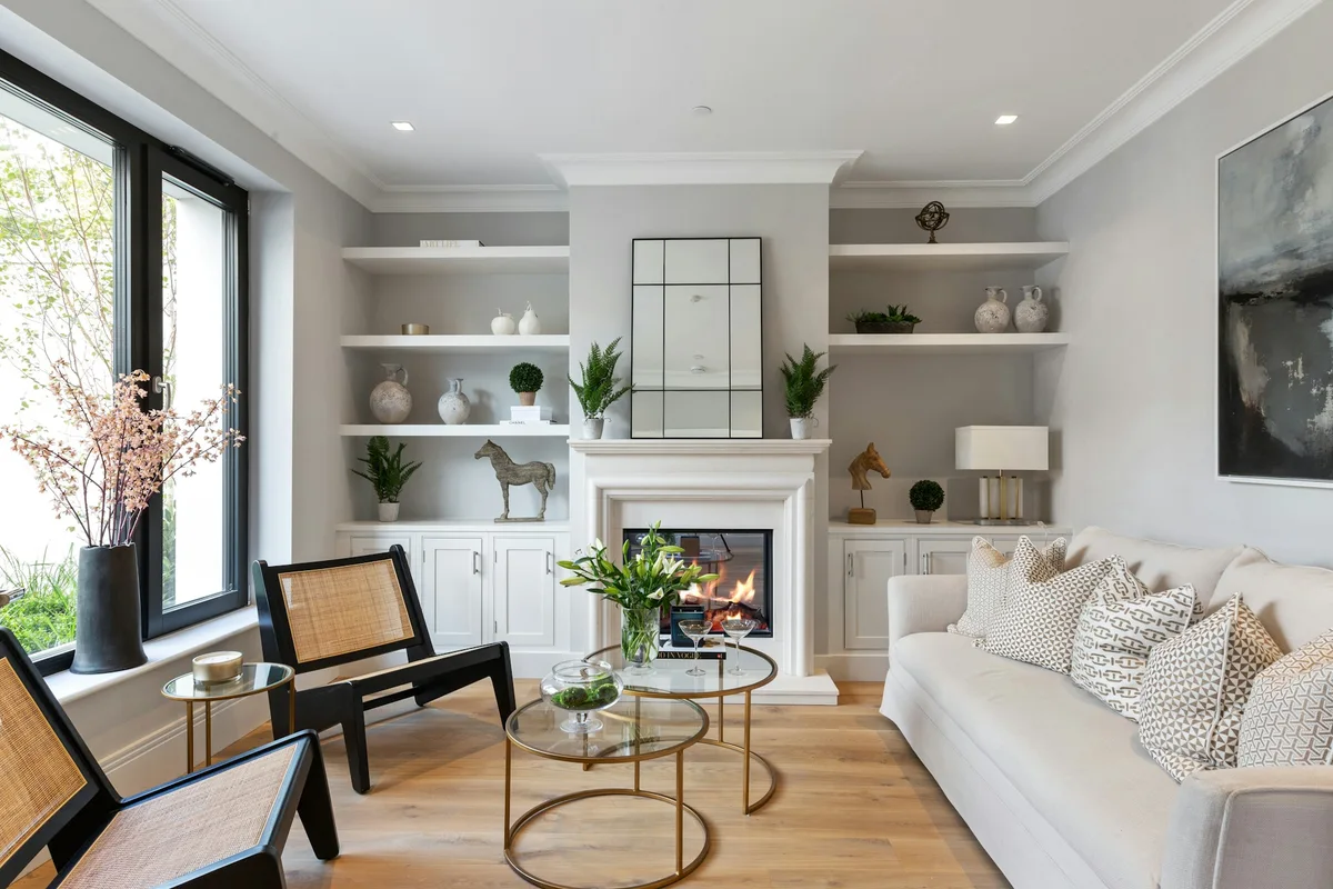 Living-room photograph showing a fireplace, shelving, windows and seating in the same wide view.