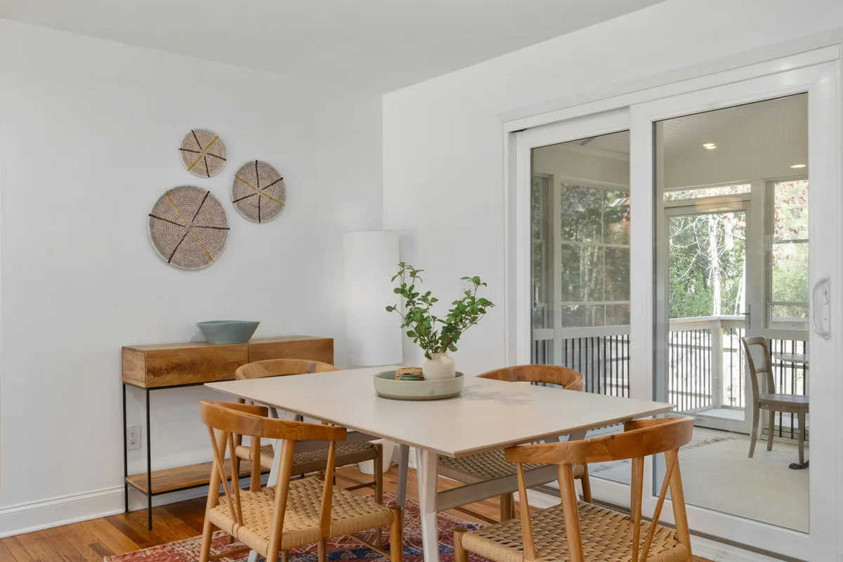 Dining table and chairs beside sliding glass doors, with the surrounding space visible.